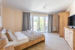 a bedroom with a large bed and a television at Ambria Apartments Centrum in Świnoujście