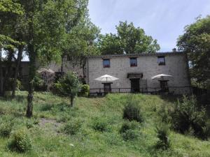 ein Gebäude mit Tischen und Sonnenschirmen auf einem Feld in der Unterkunft I Casali del Buontempo in Buggiano