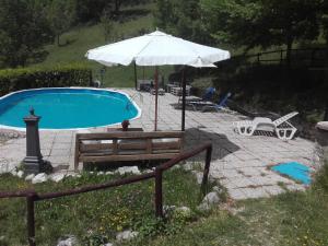 einen Pool mit einem Sonnenschirm, einer Bank, einem Tisch und einem Sonnenschirm in der Unterkunft I Casali del Buontempo in Buggiano