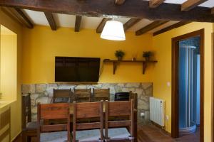 a dining room with a television and a stone wall at La Escanda in La Rebollada