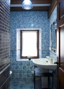 baño de azulejos azules con lavabo y ventana en La Escanda en La Rebollada