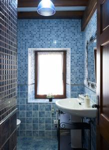 a blue tiled bathroom with a sink and a window at La Escanda in La Rebollada +22 photos