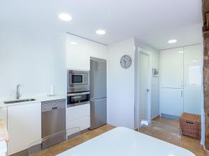 a kitchen with white cabinets and a clock on the wall at Mundaka by Aston Rentals in Mundaka