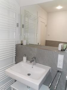 La salle de bains blanche est pourvue d'un lavabo et d'un miroir. dans l'établissement exklusives Studioapartment - in traumhafter Lage direkt am Halensee, à Berlin