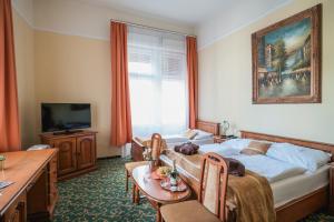 a bedroom with a bed and a table and a tv at City Hotel UNIO superior in Budapest