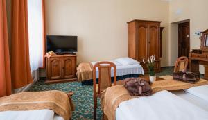 ブダペストにあるCity Hotel UNIO superiorのベッド3台とテレビが備わるホテルルームです。