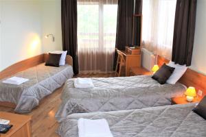 a hotel room with two beds and a desk at Guest House Brezata - Betula in Glavatartsi +49 photos