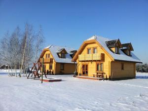 a wooden house with snow on the roof at Noclegi Gaja in Święta Katarzyna