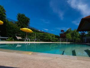 a large swimming pool with an umbrella and chairs at Hotel FleurAlp in Cermes