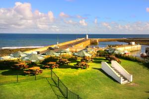 un restaurante con mesas y sombrillas junto a la playa en The Bamburgh Castle Inn - The Inn Collection Group en Seahouses