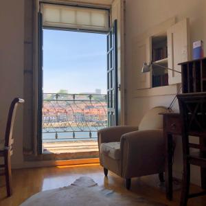 a living room with a chair and a large window at PortoSense Ribeira in Porto