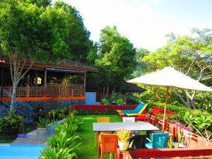un patio con mesa, sillas y sombrilla en Manggis Garden Dive Resort, en Candidasa