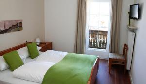 a bedroom with a bed with green pillows and a window at Gasthof Albergo Kreuzwirt in Völs am Schlern