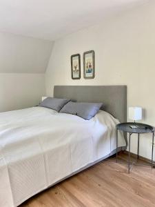 a bedroom with a large white bed and a table at Ferienwohnung Hochdorfer Garten in Tating