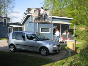 um pequeno carro prateado estacionado em frente a uma casa em Fjordlyst Camping & Cottages em Aabenraa