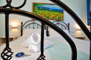 a bed with white pillows and a painting on the wall at Hotel Baia Cea in Bari Sardo