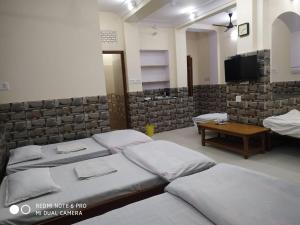 斋浦尔BOBY HOME STAY "BOBY MANSION" Jaipur的一间带四张床、一张桌子和电视的房间 更多31张照片