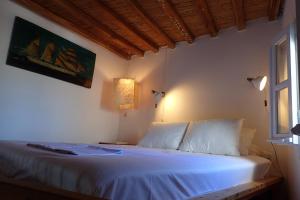 Un dormitorio con una cama con sábanas blancas y una ventana. en Eastern Wind Home, en Skiros