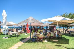 grupa ludzi siedzących przy stołach pod parasolami w obiekcie Pinelopi Beach Suites w mieście Georgioupolis +34 zdjęcia