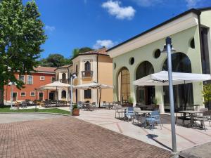 a courtyard with tables and chairs and umbrellas at Hotel Alle Acque in Lonigo