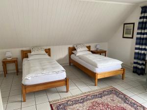 two beds in a room with two tables and a rug at Ferienwohnungen Schewe I in Bad Eilsen
