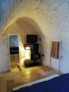 Pokój z łóżkiem i telewizorem w kamiennej ścianie w obiekcie Le Terrazze Ferrigni w mieście Ostuni