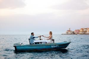 a man and a woman sitting in a blue boat at Vila Piranesi Apartments - Parking included in Piran