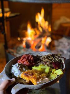 a person holding a plate of food in front of a fireplace at Lucky Ranch cabin 4 in Pyhätunturi