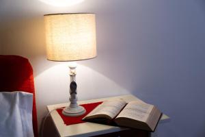 eine Lampe auf einem Tisch mit einem offenen Buch in der Unterkunft Residence Ferraud in Pinerolo