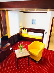 a hotel room with a yellow chair and a couch at Kurhotel Wiedenmann in Bad Wörishofen