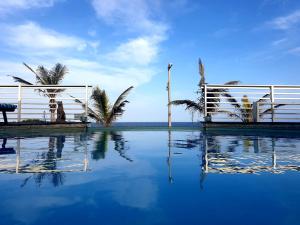 a swimming pool with palm trees and a white fence at Bentley on the Beach in Umhlanga