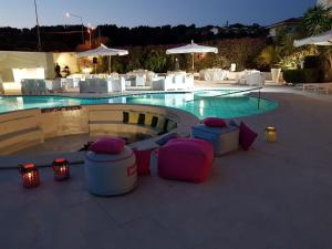 a swimming pool with pink and purple ottomans and chairs in front at Sunshine Club Hotel Centro Benessere in Ricadi
