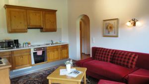 a living room with a red couch and a kitchen at Ferienwohnungen Birnbacher in Sankt Ulrich am Pillersee