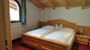 a bedroom with a bed with white sheets and a window at Ferienwohnungen Birnbacher in Sankt Ulrich am Pillersee