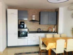 a kitchen with white cabinets and a wooden table at Apartment Svetlana in Selce
