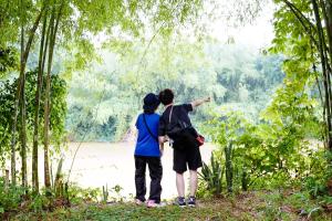 dos personas de pie en un bosque mirando un río en Green Hope Lodge, en Cát Tiên