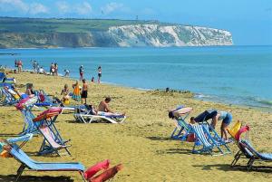 a group of people on a beach with lawn chairs at The Denewood in Sandown