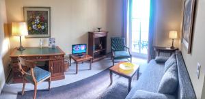 a living room with a couch and a desk and a tv at Hotel Wilder Mann Annaberg-Buchholz in Annaberg-Buchholz
