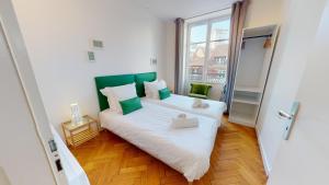 ein Schlafzimmer mit einem weißen Bett mit einem grünen Kopfteil in der Unterkunft Strasbourg Appart Rue du 22 Novembre in Straßburg