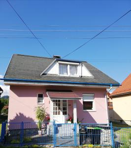 ein rosa Haus mit einem blauen Zaun in der Unterkunft Villa Strakov in Lúčky