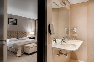 a hotel room with two sinks and a mirror at Amberton Cathedral Square Hotel Vilnius in Vilnius