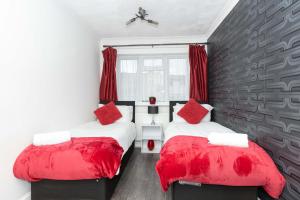 two beds in a room with red pillows at CAPRI 13 SA - 3 Bedroom House close to Loughborough University, EV car facilities, Free Parking, Free Wifi - Ask for contractor rates! in Loughborough