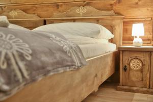 a bed with a wooden headboard and a table with a lamp at Agroturystyka Pokoje na Zakręcie in Białka Tatrzańska