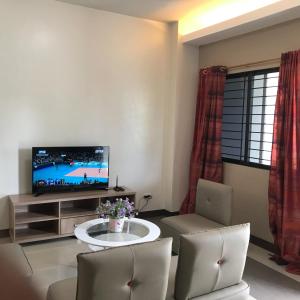- un salon avec une télévision, une table et des chaises dans l'établissement Sajo Plaza & Residences, à Iloilo