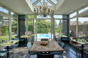 una sala da pranzo con tavolo, sedie e piscina di B&B De Joker a Turnhout