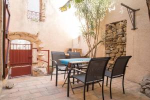 een patio met een tafel en stoelen en een stenen muur bij A l'ombre du bananier in Néffiès