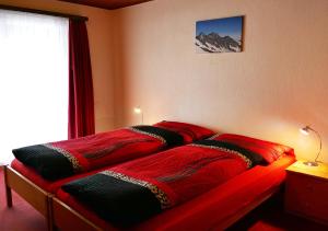 1 dormitorio con 2 edredones rojos en una cama en Alba, en Saas-Fee