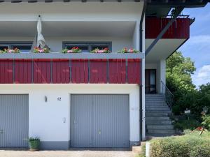 une maison avec deux portes de garage et des fleurs sur le balcon dans l'établissement Ferienhaus Keller, à Lippertsreute