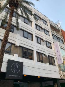 a white building with a sign in front of a palm tree at Backpacker 41 Hostel - Taichung in Taichung