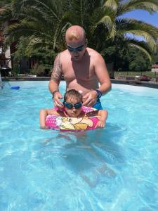 um homem e uma criança numa piscina em Apartamentos El Rincon Encantado em Llano-Con